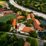 Aerial view of a prestigious international school campus with modern sports facilities and nearby residential neighbourhoods, illustrating family-friendly living close to Marbella's top international schools